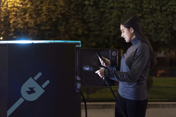 Female using a commercial EV charger at night