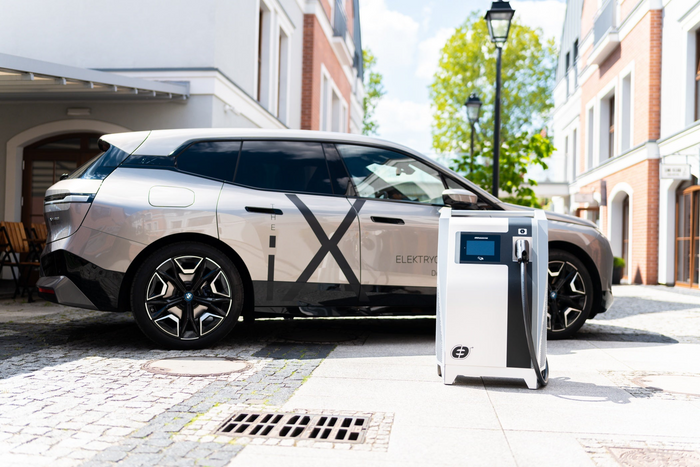 An electric car parked up on a cobbled street, charging at a ekoenergetyka plug charger go