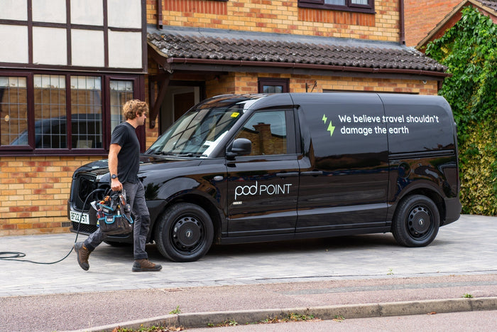 A POD installer walking back to their POD branded van, carrying technical equipment